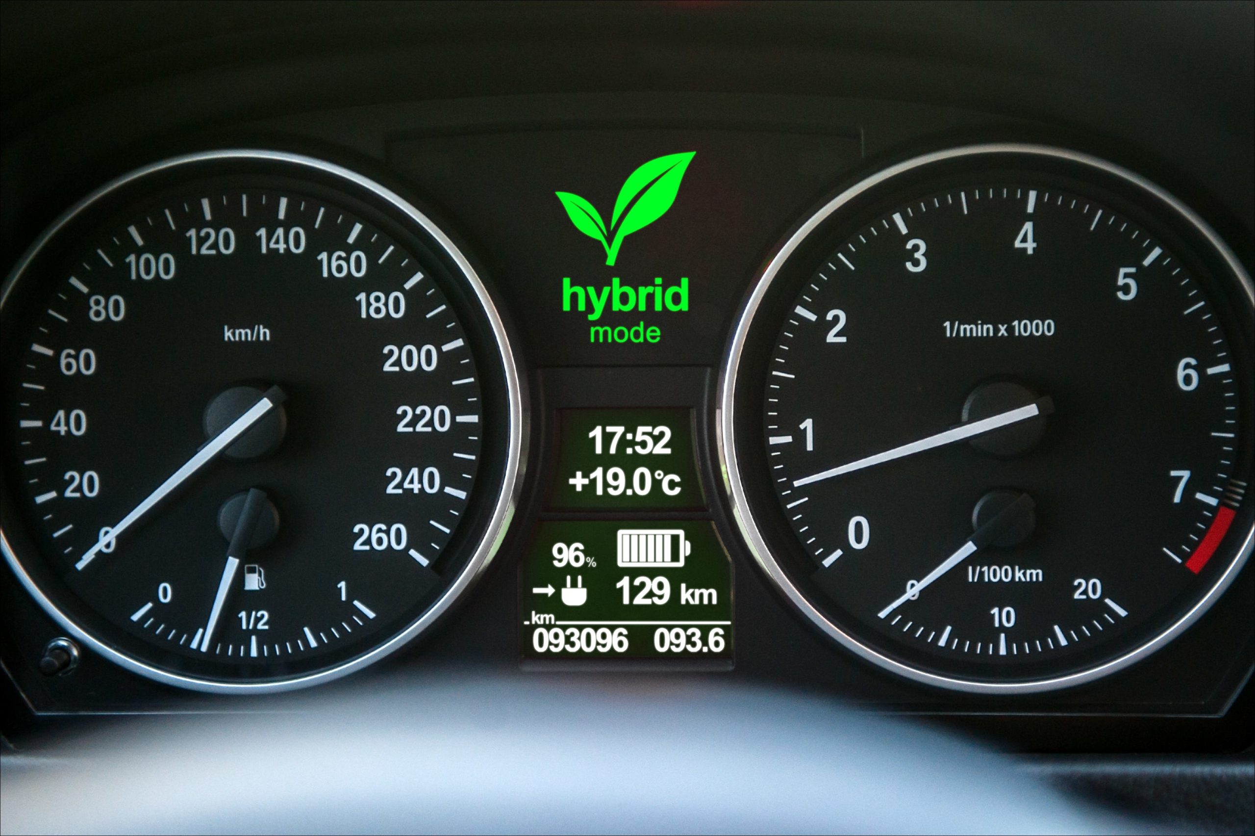 Closeup da tela do painel de um carro híbrido com a luz "Modo Híbrido" ativada.