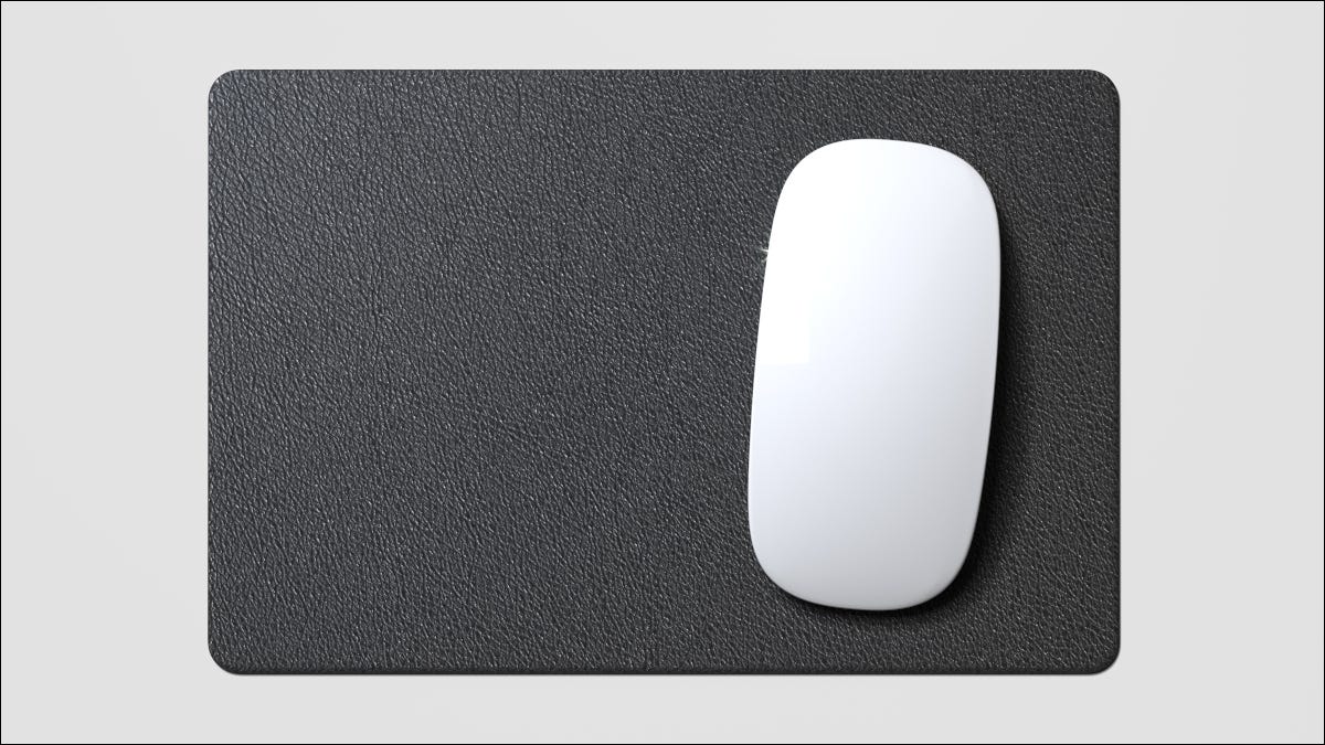 Um mouse branco em um mouse pad preto.