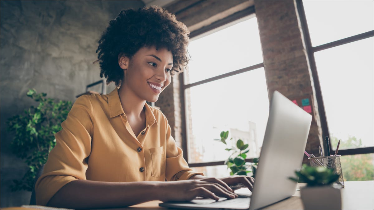 Mulher sorrindo enquanto estiver usando um laptop.