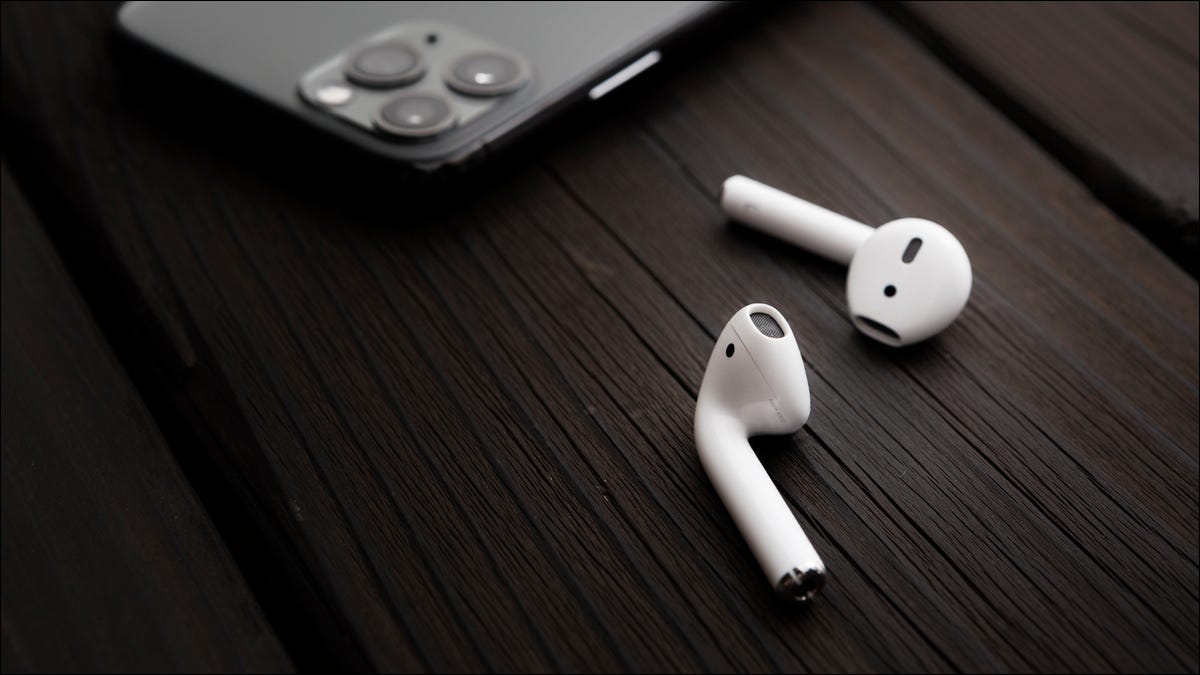 AirPods em uma mesa ao lado de um iPhone.