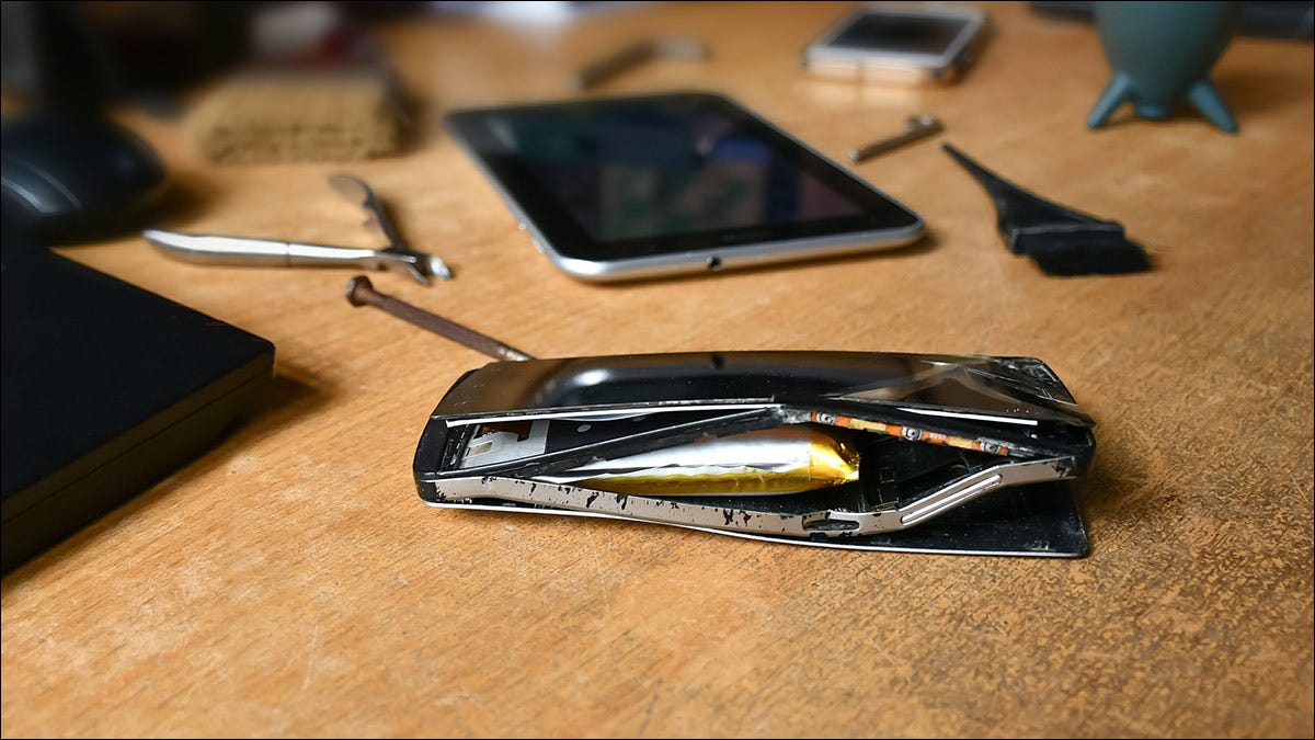 Um telefone com uma bateria inchada, sentado em um banco de reparos.