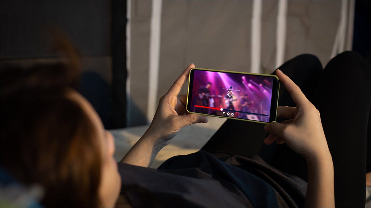 Um adolescente assistindo a um streaming de vídeo em seu telefone.