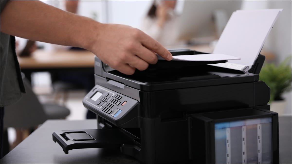 Uma pessoa usando uma impressora multifuncional em um ambiente de escritório.