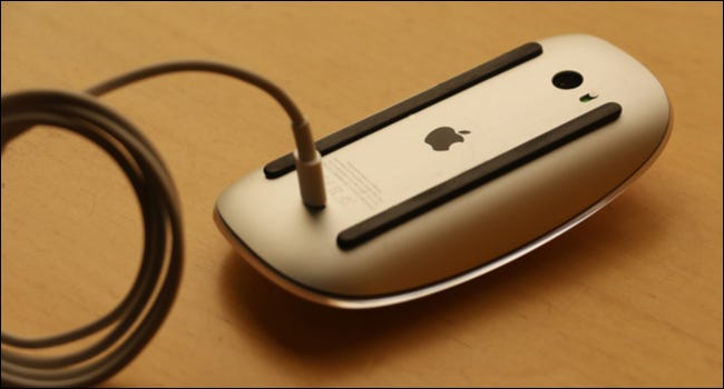 Um mouse Apple de cabeça para baixo com o cabo de carregamento conectado.