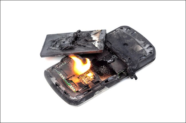 Um celular em chamas com uma bateria explodida.