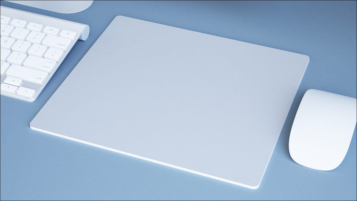 Um mousepad branco moderno do computador ao lado de um mouse e um teclado.