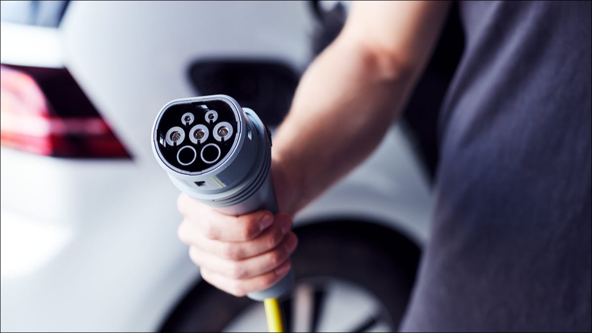 Pessoa segurando um carregador de carro elétrico.