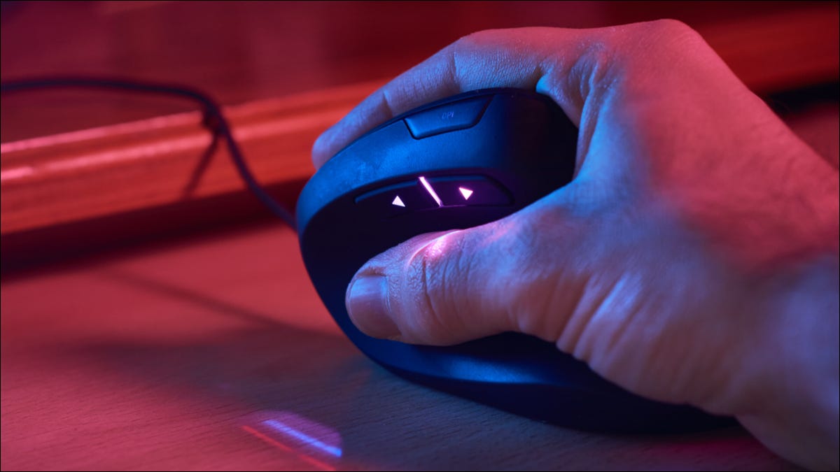 Close da mão de uma pessoa em um mouse ergonômico sob iluminação RGB.