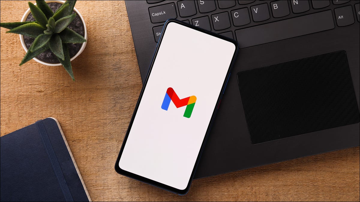 Logotipo do Gmail em um smartphone ao lado de um computador