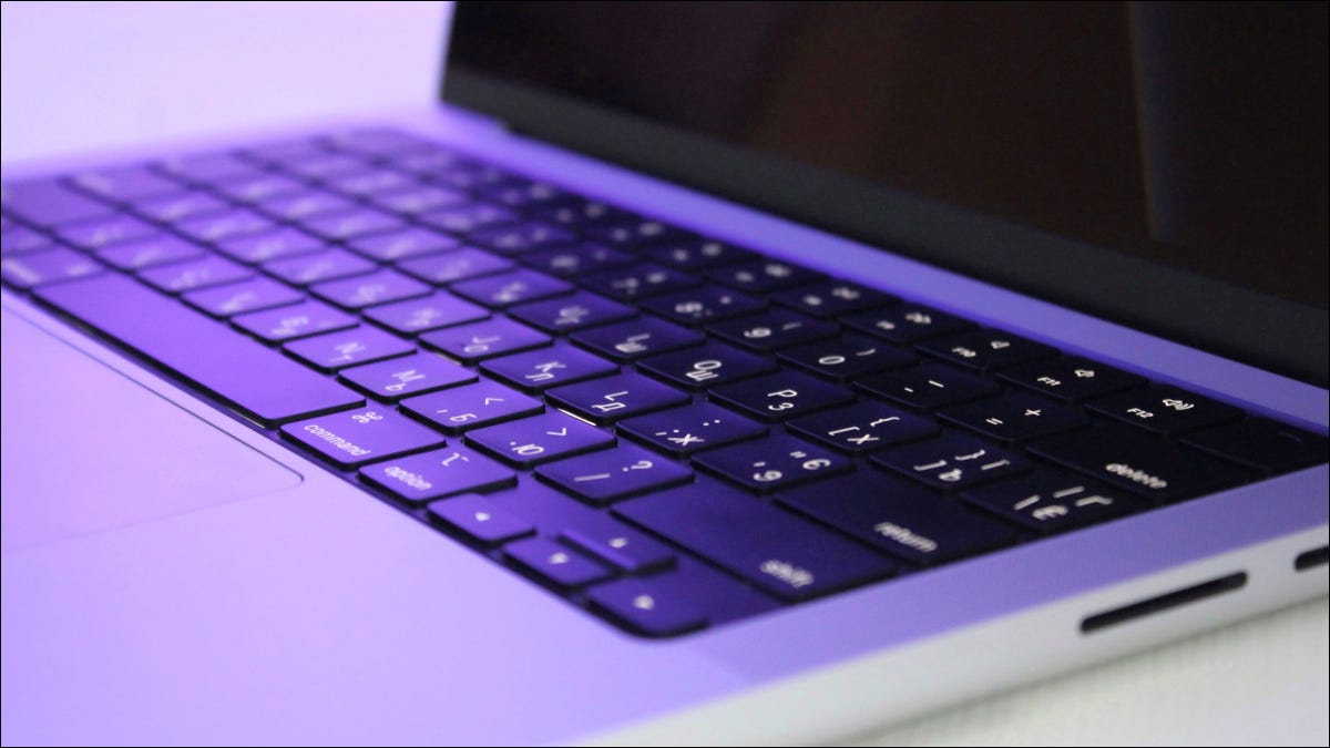 Close de um MacBook Pro M1 sob iluminação roxa.