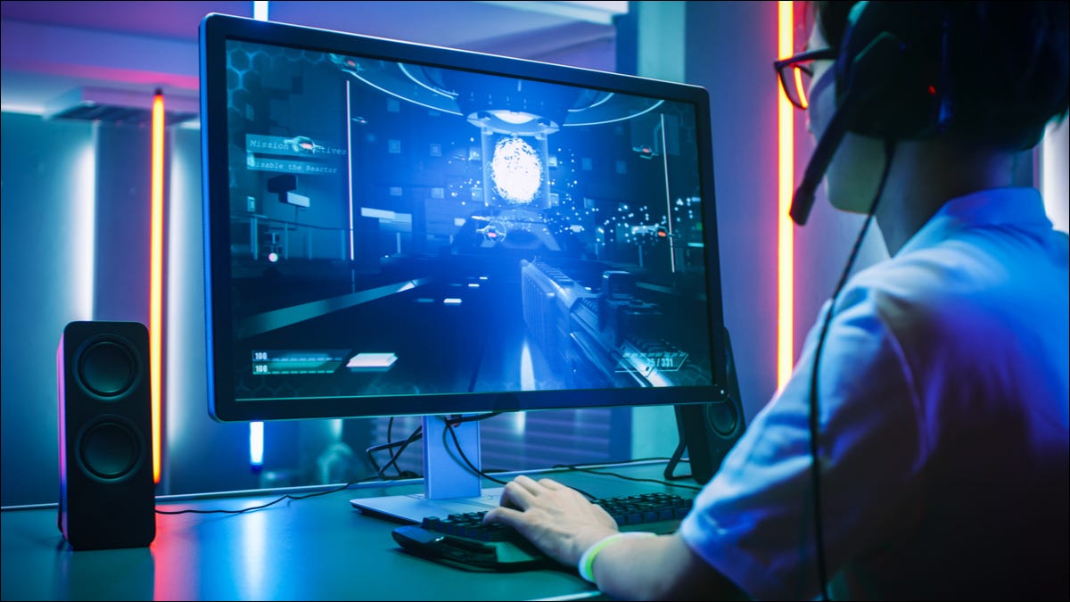 Visão traseira de um jogador profissional usando um monitor de PC de última geração.