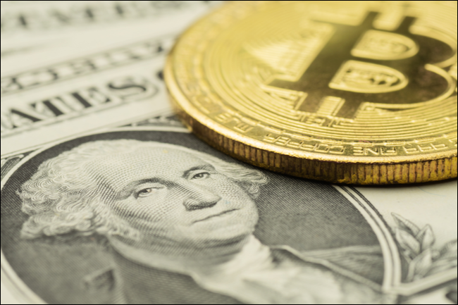 Um token Bitcoin e uma nota de dólar.