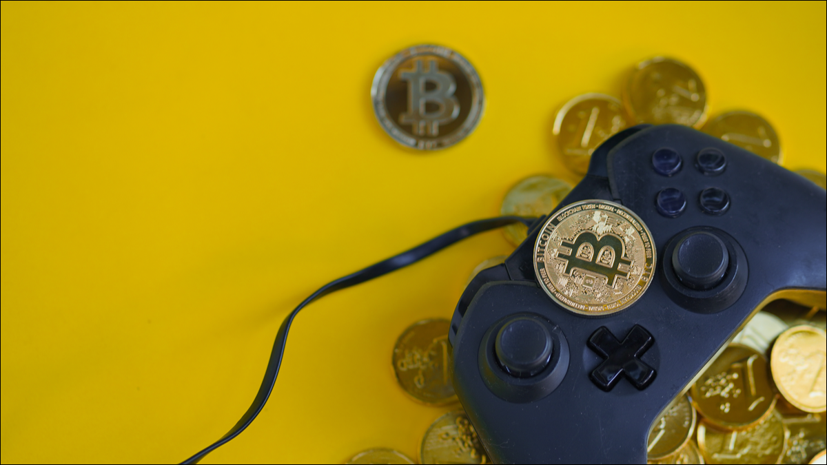 Um controlador de jogo cercado por Bitcoin e outros tokens de criptomoeda.