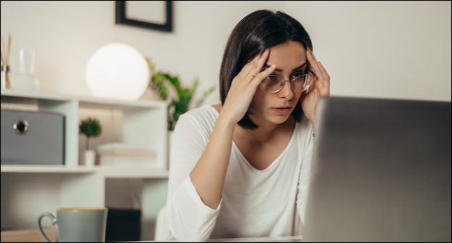 Mulher olhando para um laptop com uma expressão estressada.