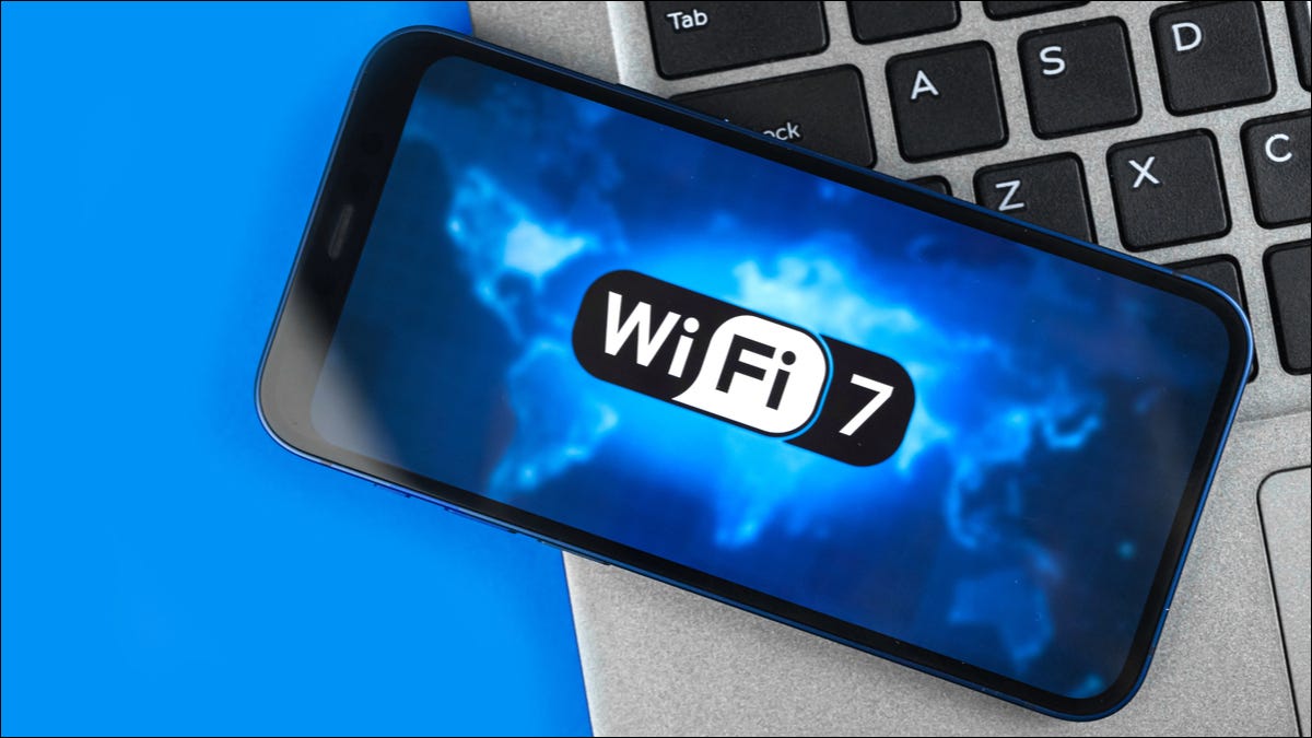 Smartphone em cima de um laptop, mostrando o logotipo do Wi-Fi 7 em exibição.