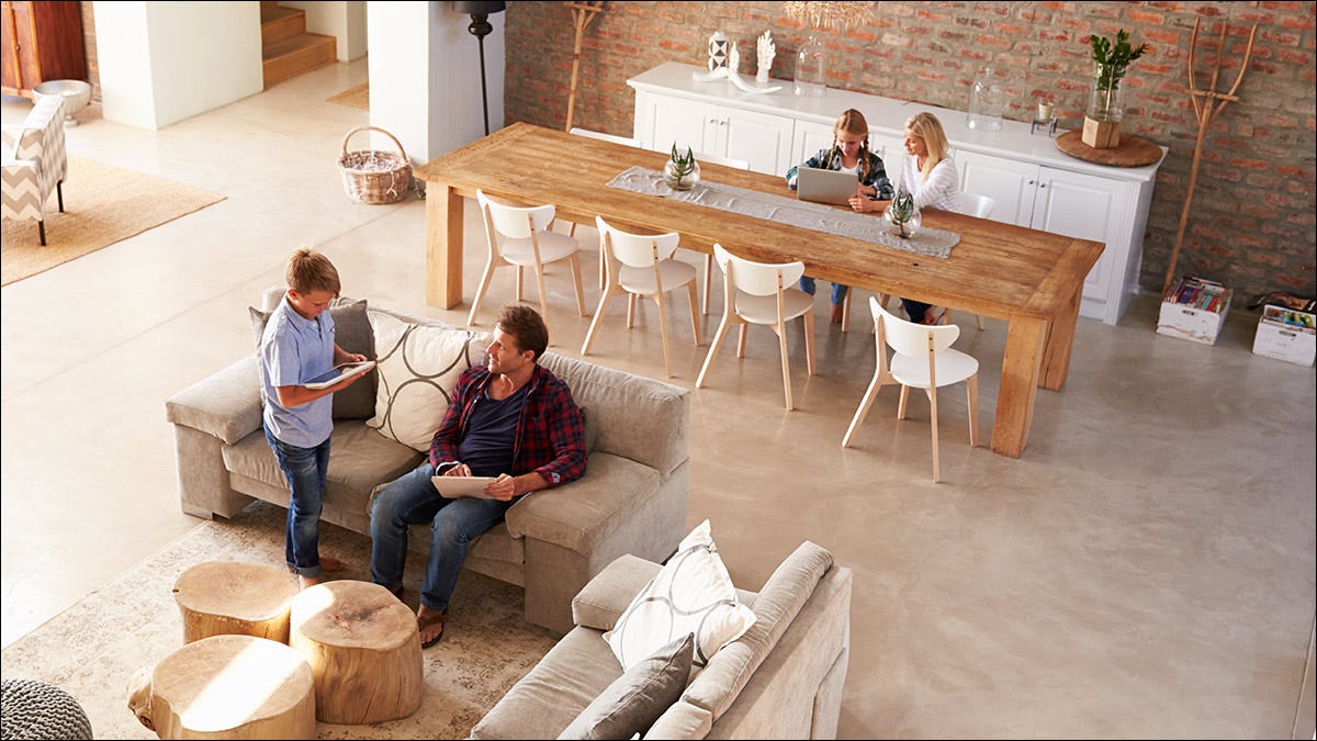 Uma família usando tablets e laptops em um espaço arejado de conceito aberto.