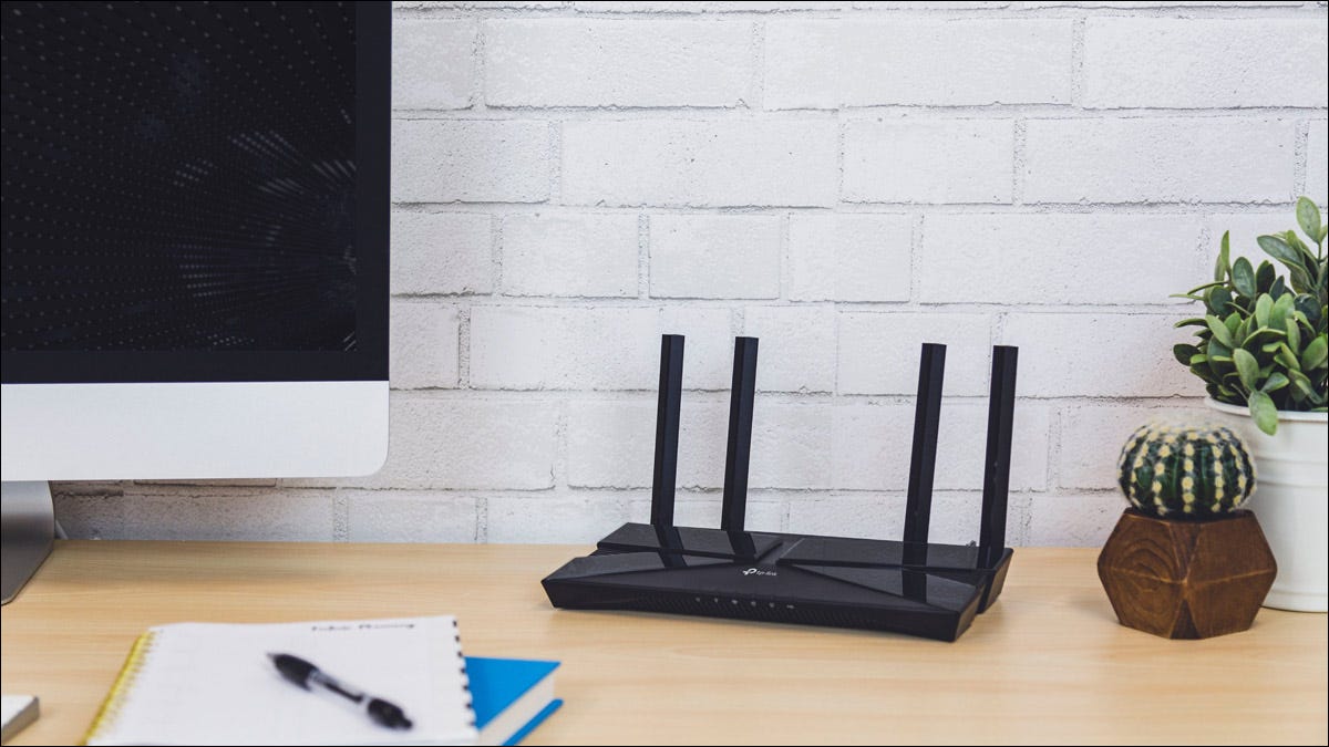 Um roteador Wi-Fi sentado em uma mesa de escritório em casa ao lado de um computador e notebooks.