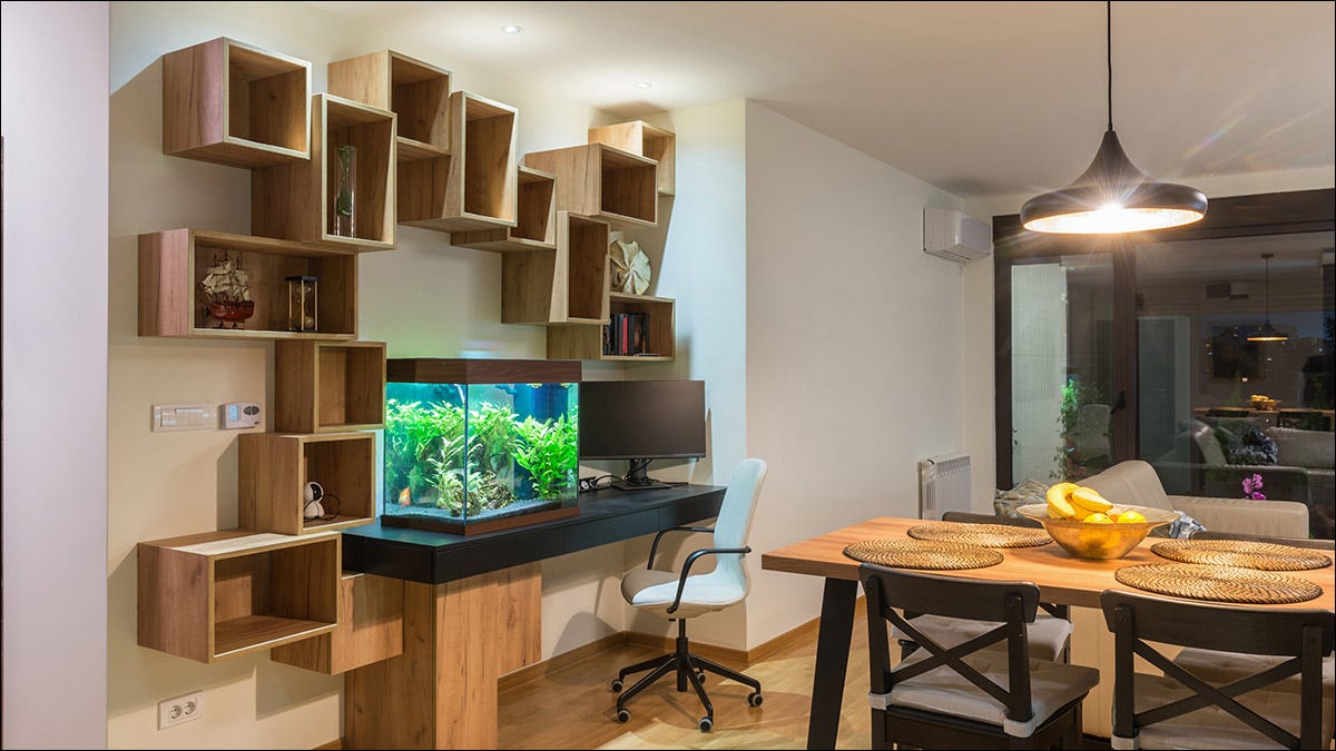 Uma sala de jantar com uma mesa montada na parede segurando um tanque de peixes.