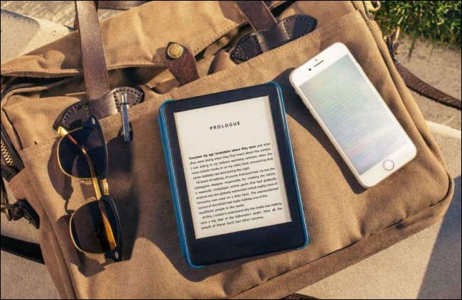 kindle no caso na bolsa de lona com telefone e óculos de sol