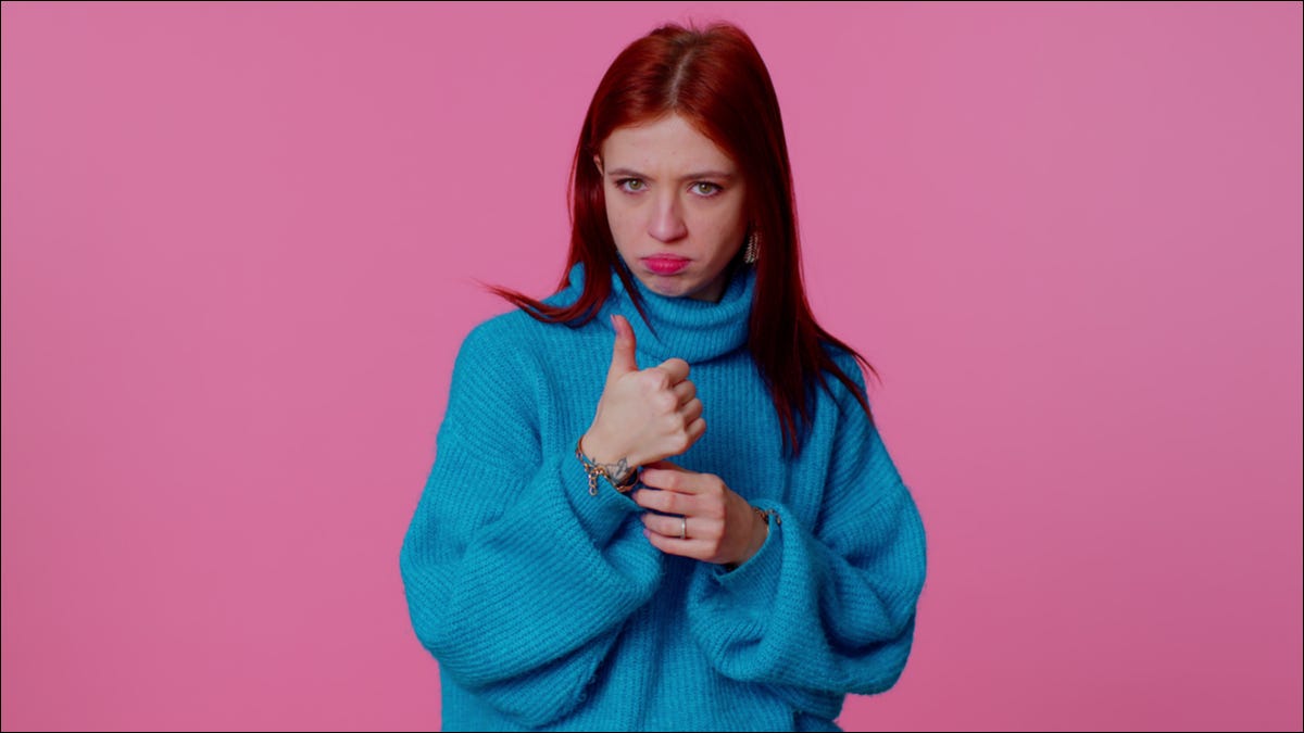 Uma jovem de suéter azul fazendo um gesto de polegar para cima.