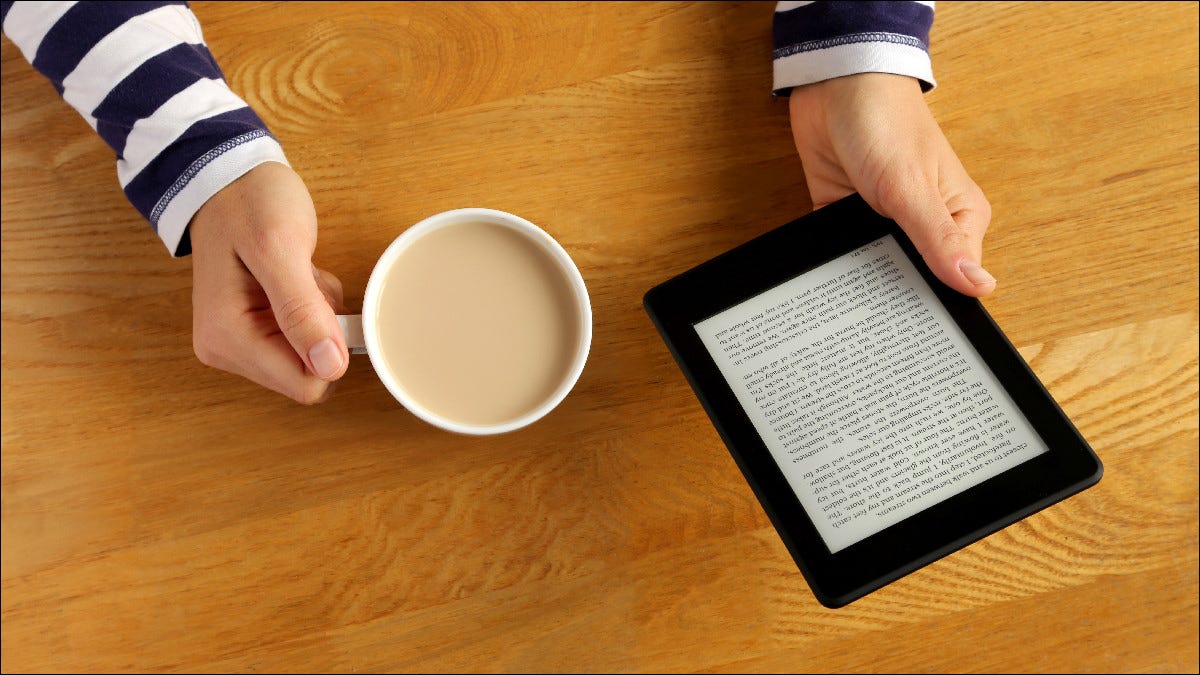 Pessoa lendo Kindle enquanto toma café.