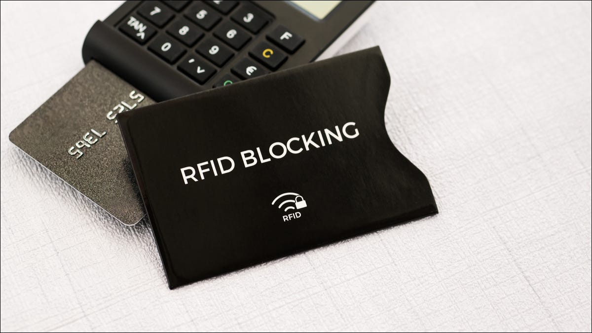 Uma manga de bloqueio de RFID com um cartão de crédito em um leitor de cartão atrás dele.