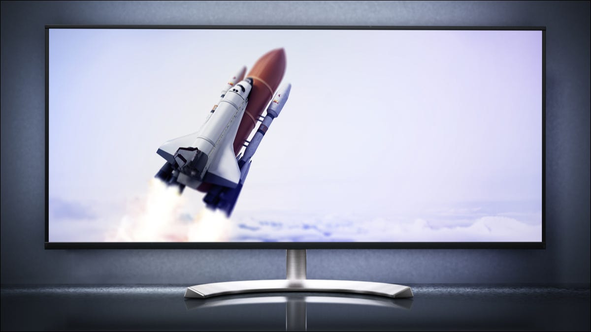 Um monitor de computador ultra-amplo com um lançamento de ônibus espacial em exibição.