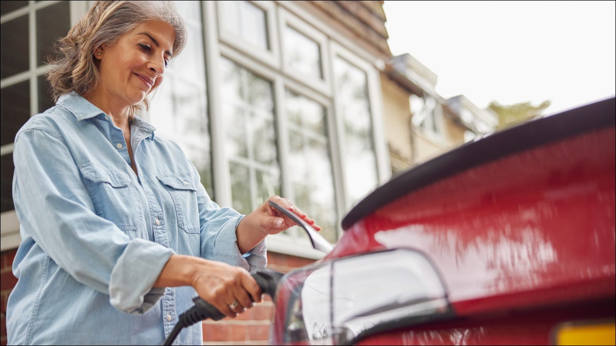 Mulher carregando um carro elétrico em casa.