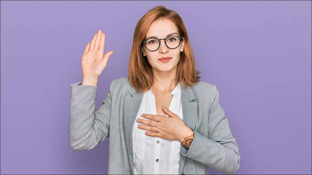 Mulher em trajes de negócios fazendo gesto de juramento.