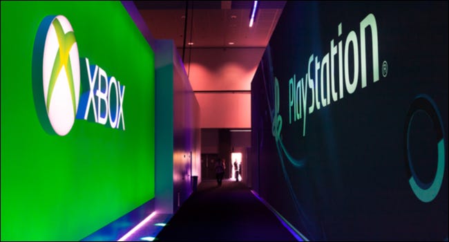 Corredor em uma conferência de jogos com o logotipo do Xbox de um lado e o logotipo do PlayStation do outro.