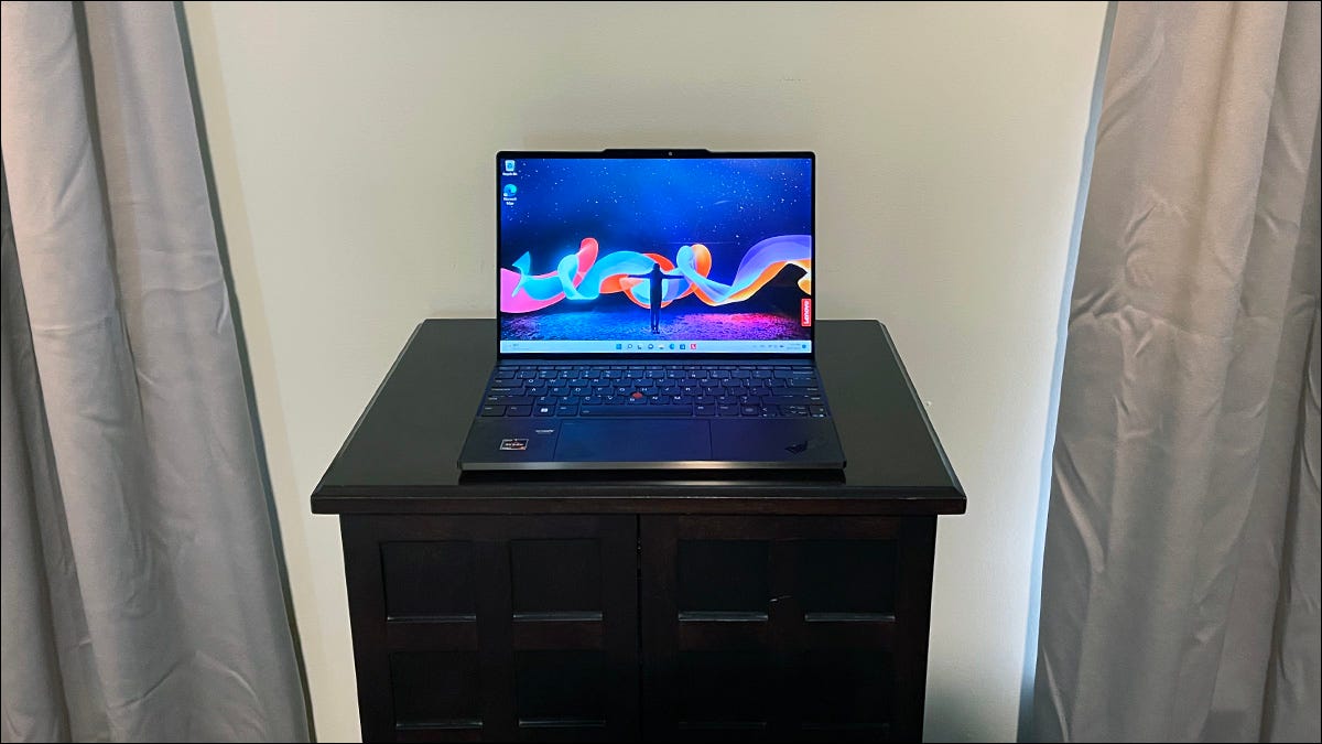 Um notebook com tela sensível ao toque Lenovo ThinkPad Z13 Gen 1 aberto em uma mesa entre duas cortinas