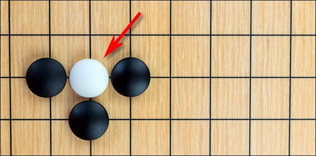 Neste diagrama do jogo de tabuleiro Go, a peça branca está em "atari".