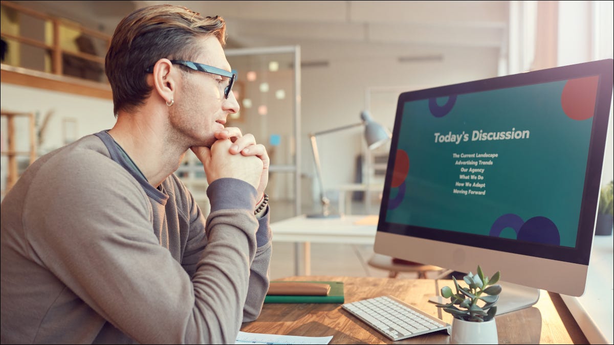 Um homem assistindo a uma apresentação de slides na tela do computador.