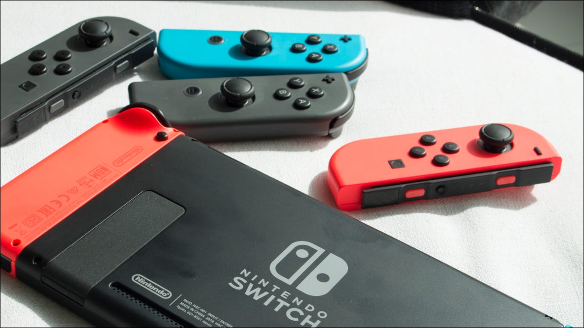 Um Nintendo Switch virado para baixo em uma mesa branca com joy-cons ao seu redor.