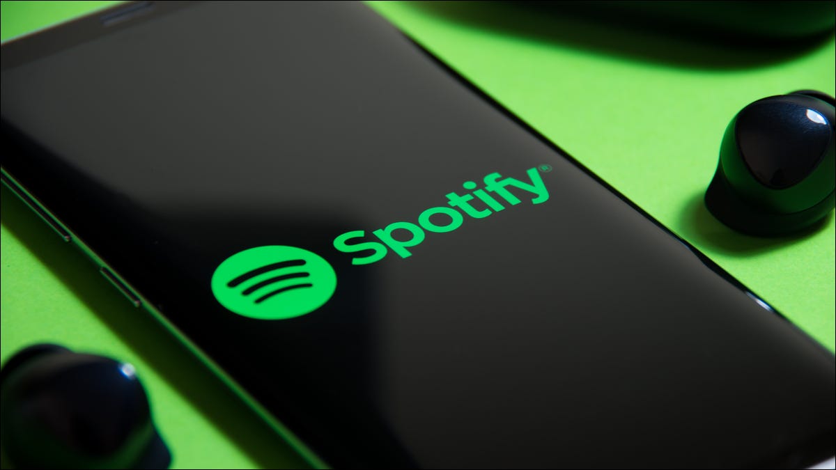 Logo Spotify em um smartphone ao lado de fones de ouvido verdadeiramente sem fio