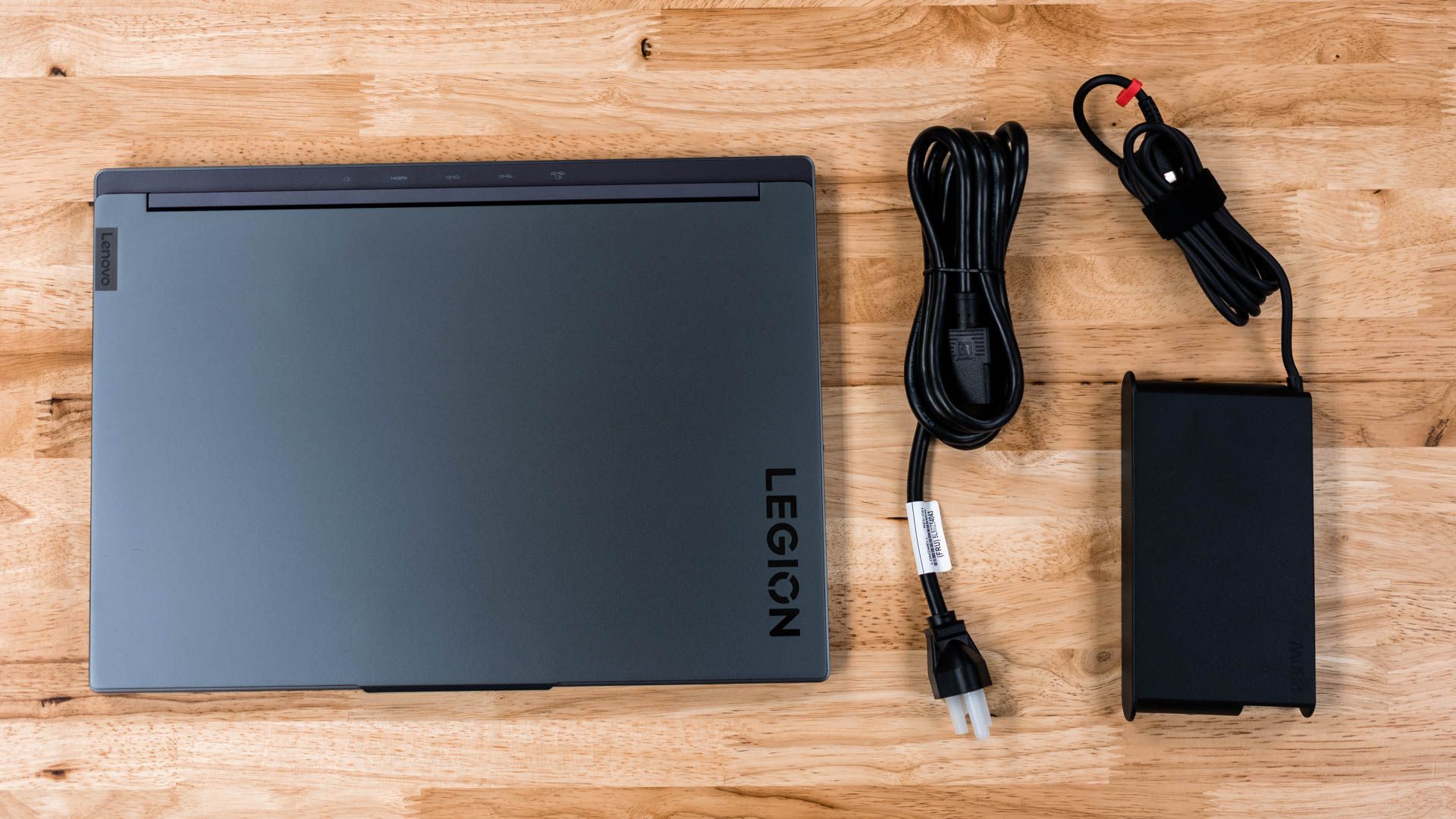 Lenovo Legion Slim 7i ao lado de seu adaptador AC