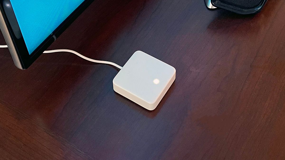 SwitchBot Hub Mini em uma mesa ao lado de uma TV e barra de som