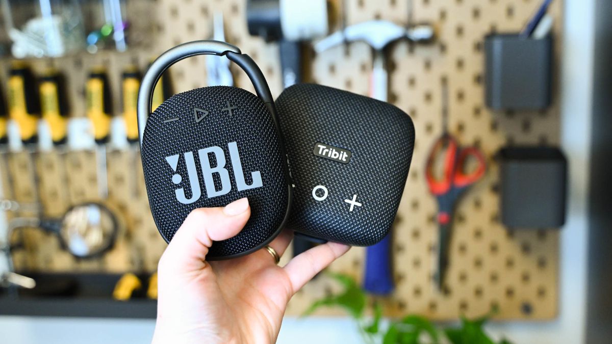 Mão de uma pessoa segurando um alto-falante Bluetooth Tribit StormBox Micro 2 no JBL Clip 4.