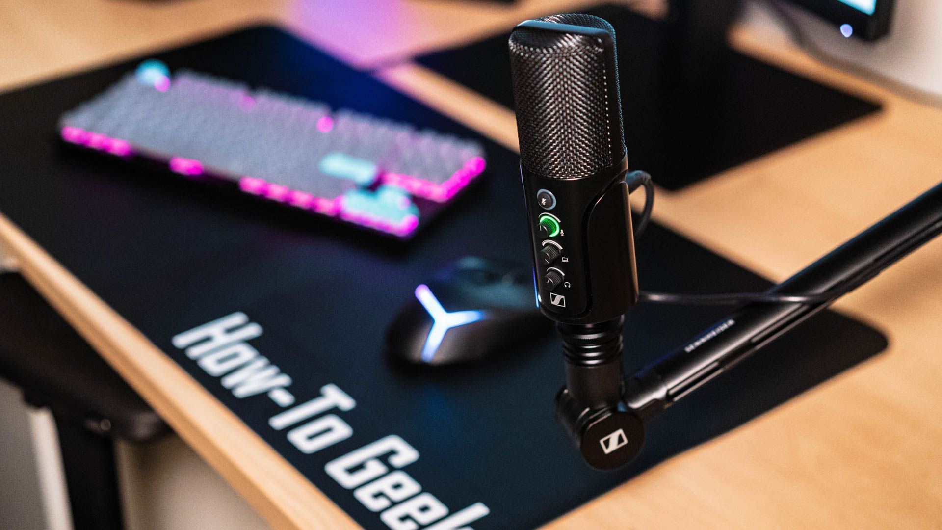 Sennheiser Profile USB Mic em uma mesa com teclado LED e tapete de mesa How-To Geek