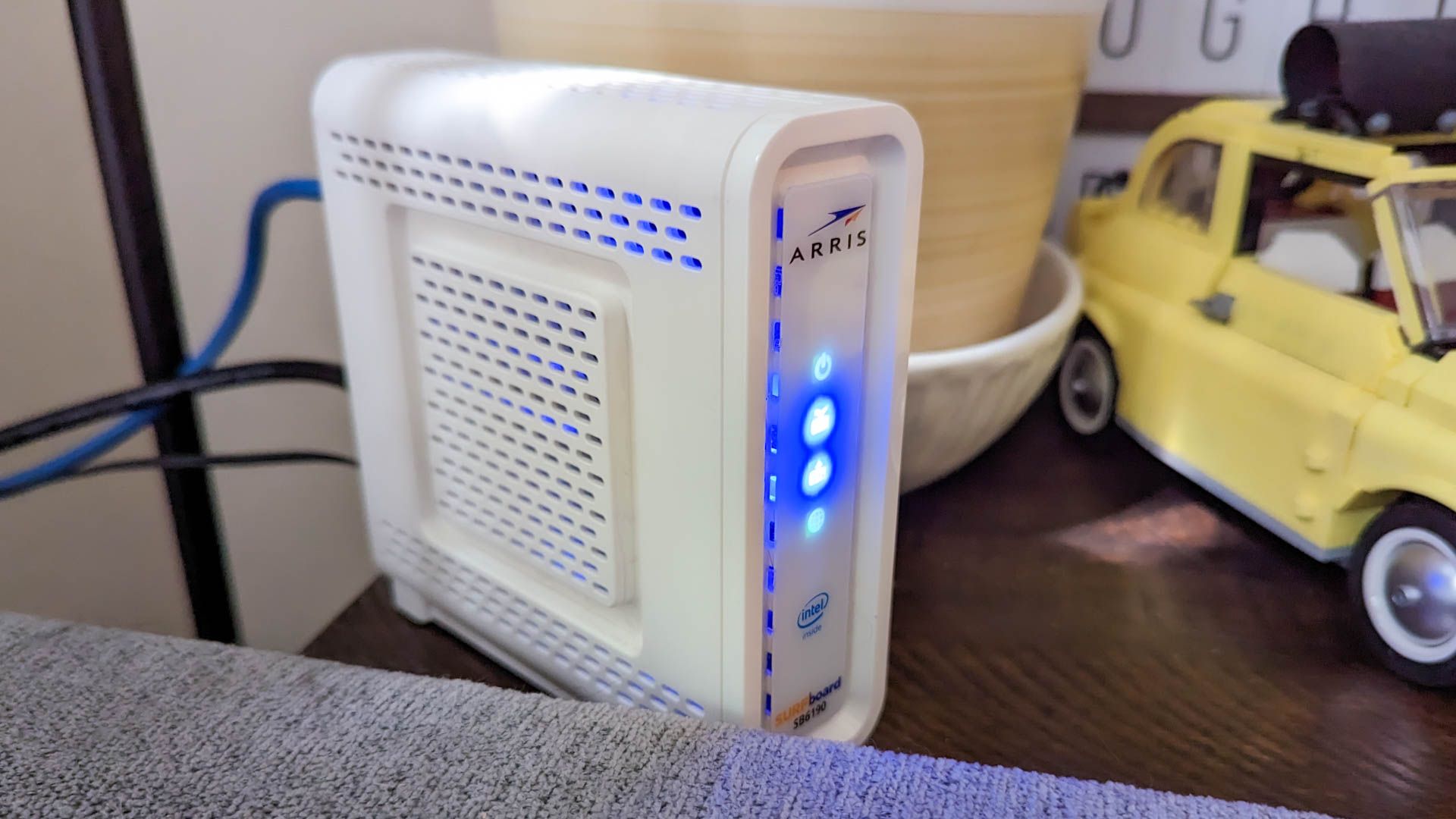 Um modem Arris instalado atrás de um sofá