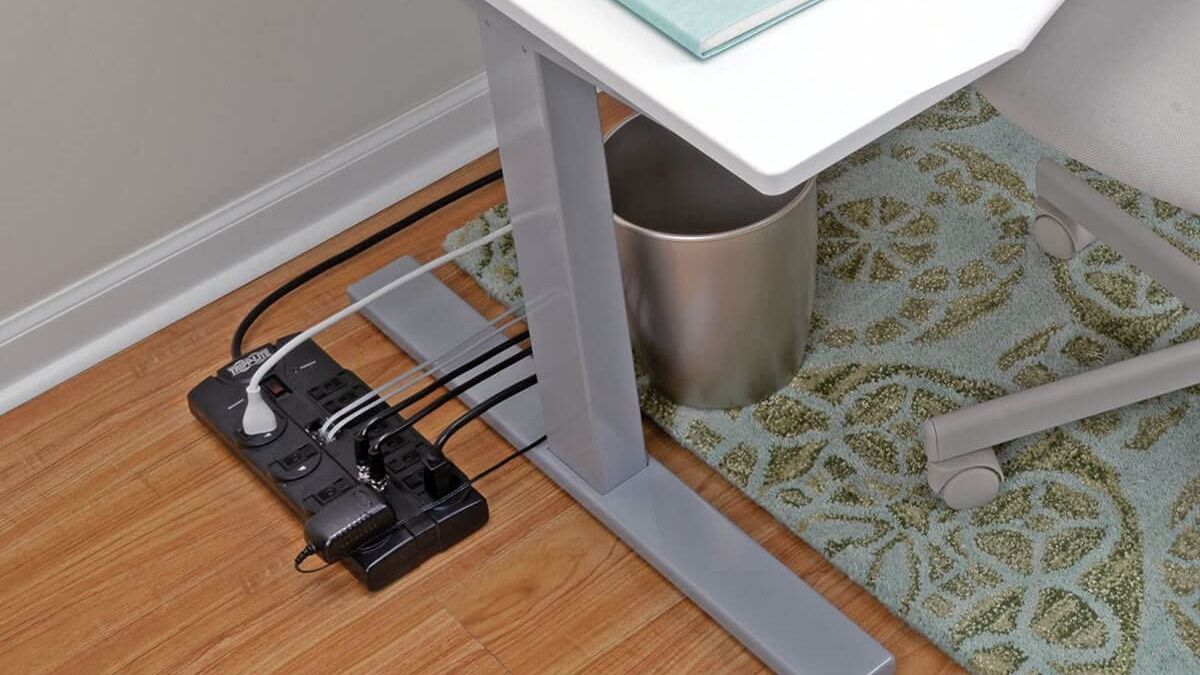 Um protetor contra surtos Tripp Lite em uso embaixo de uma mesa.