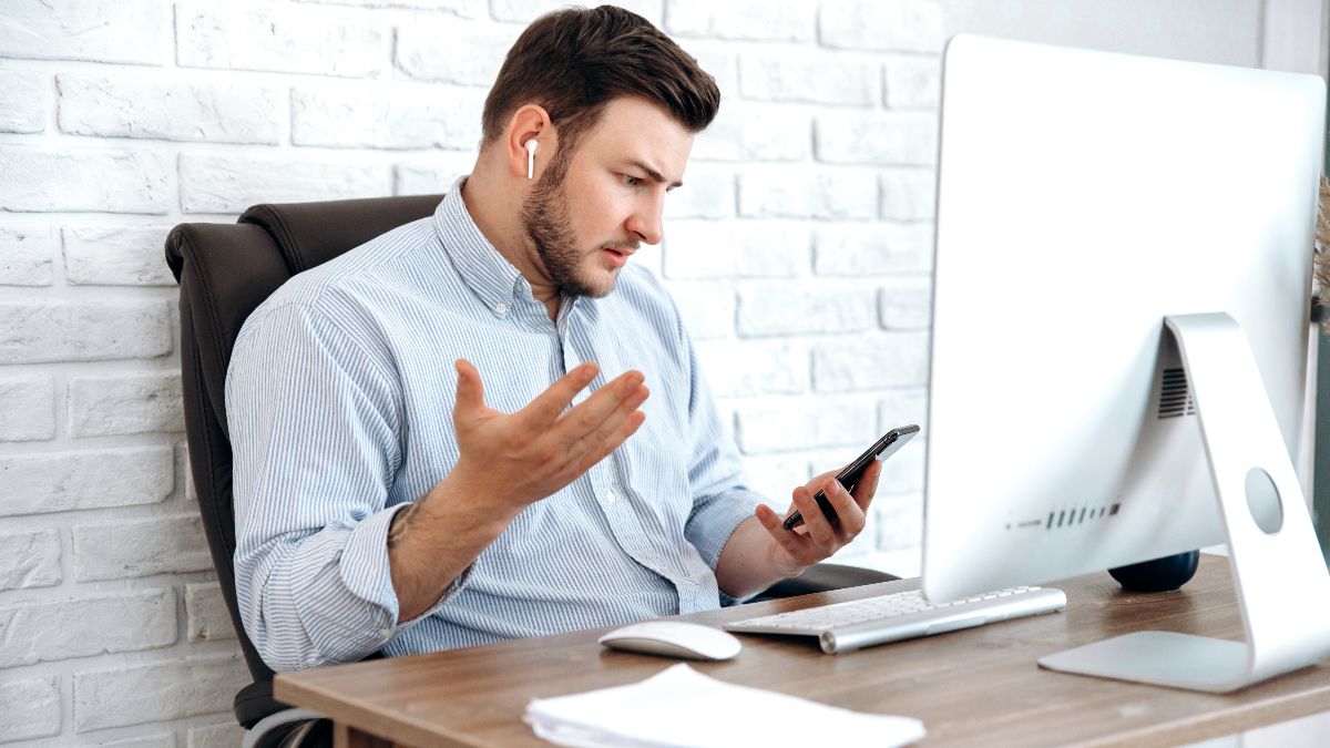 Homem usando AirPods e olhando surpreso para seu iPhone