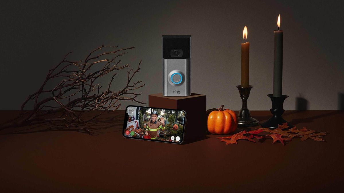 Uma campainha e um smartphone, rodeados por uma decoração de Halloween.