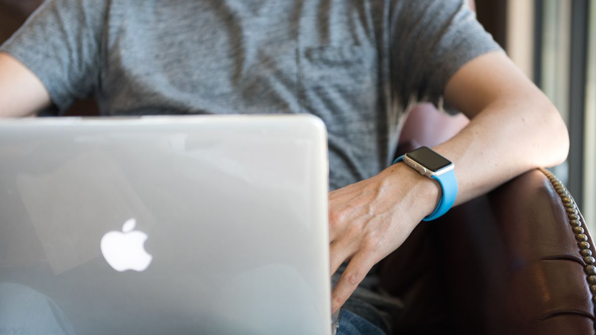 Homem usando um MacBook enquanto usa um Apple Watch