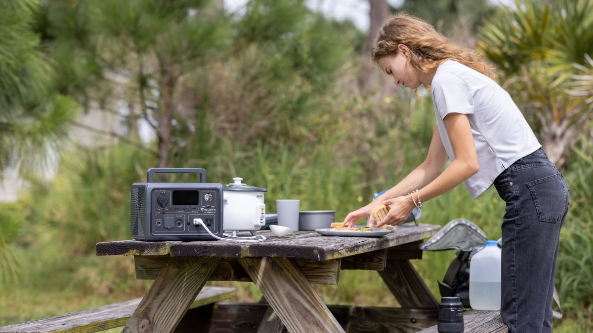 BLUETTI EB3A sentado em uma mesa de acampamento alimentando uma panela elétrica