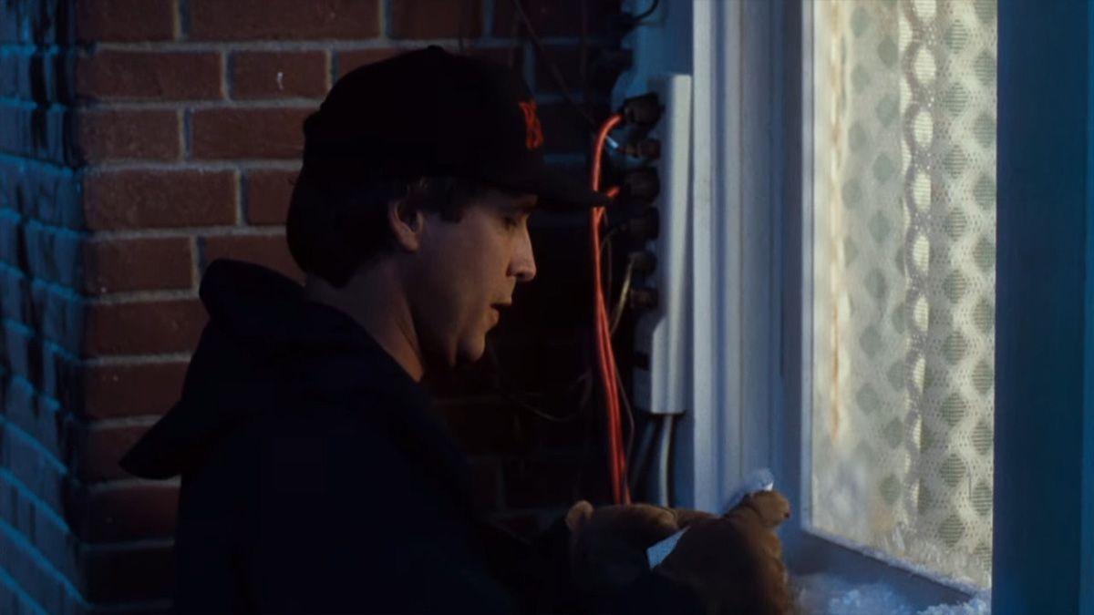 Um homem verificando seus planos de luz de Natal ao lado de um filtro de linha sobrecarregado.