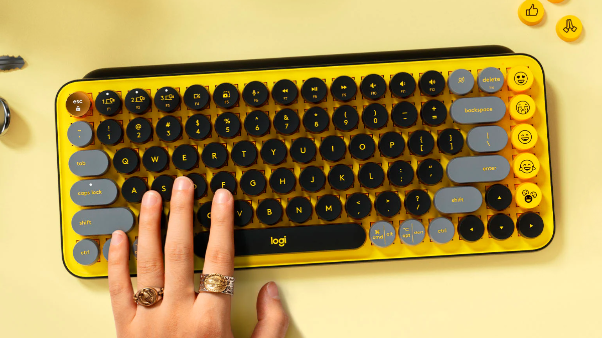 Teclado mecânico sem fio Logitech POP Keys sentado em uma mesa com uma mão digitando nele