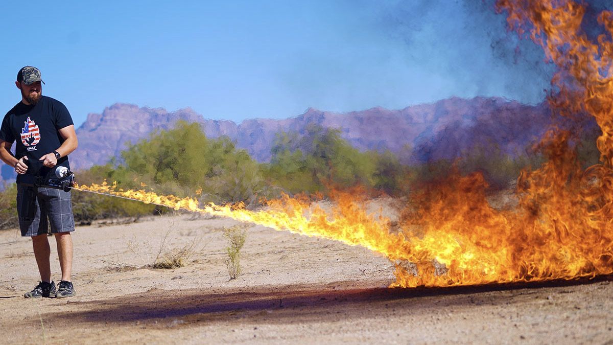 Um homem usando um lança-chamas no deserto.