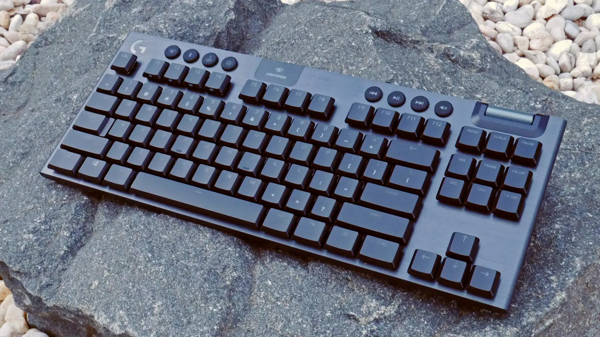 Teclado Logitech G915 TKL sentado em uma pedra