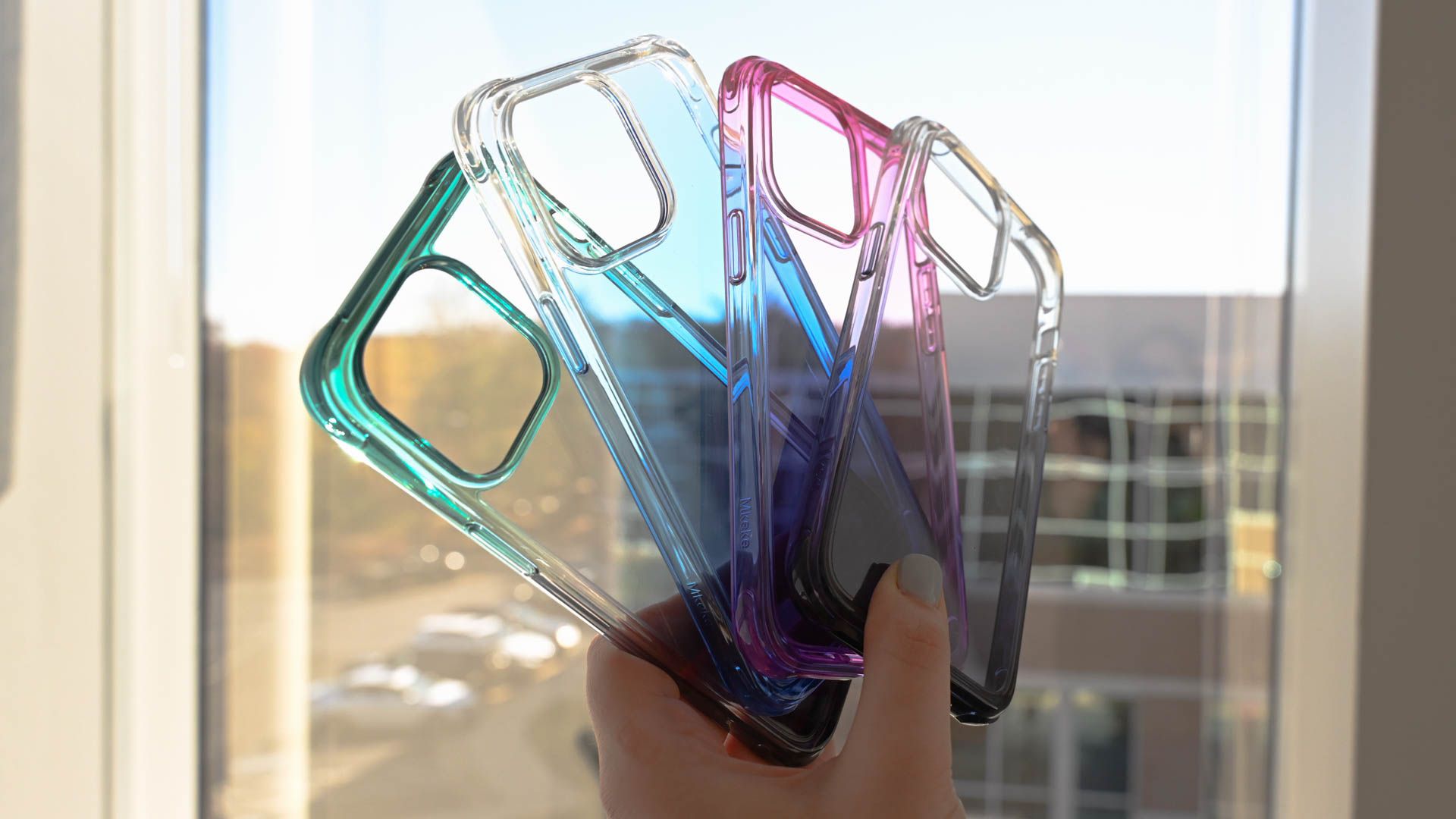 Pessoa segurando capas coloridas Mkeke transparentes para iPhone 14 Pro